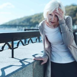 Woman with hearing loss having a dizzy spell outside.