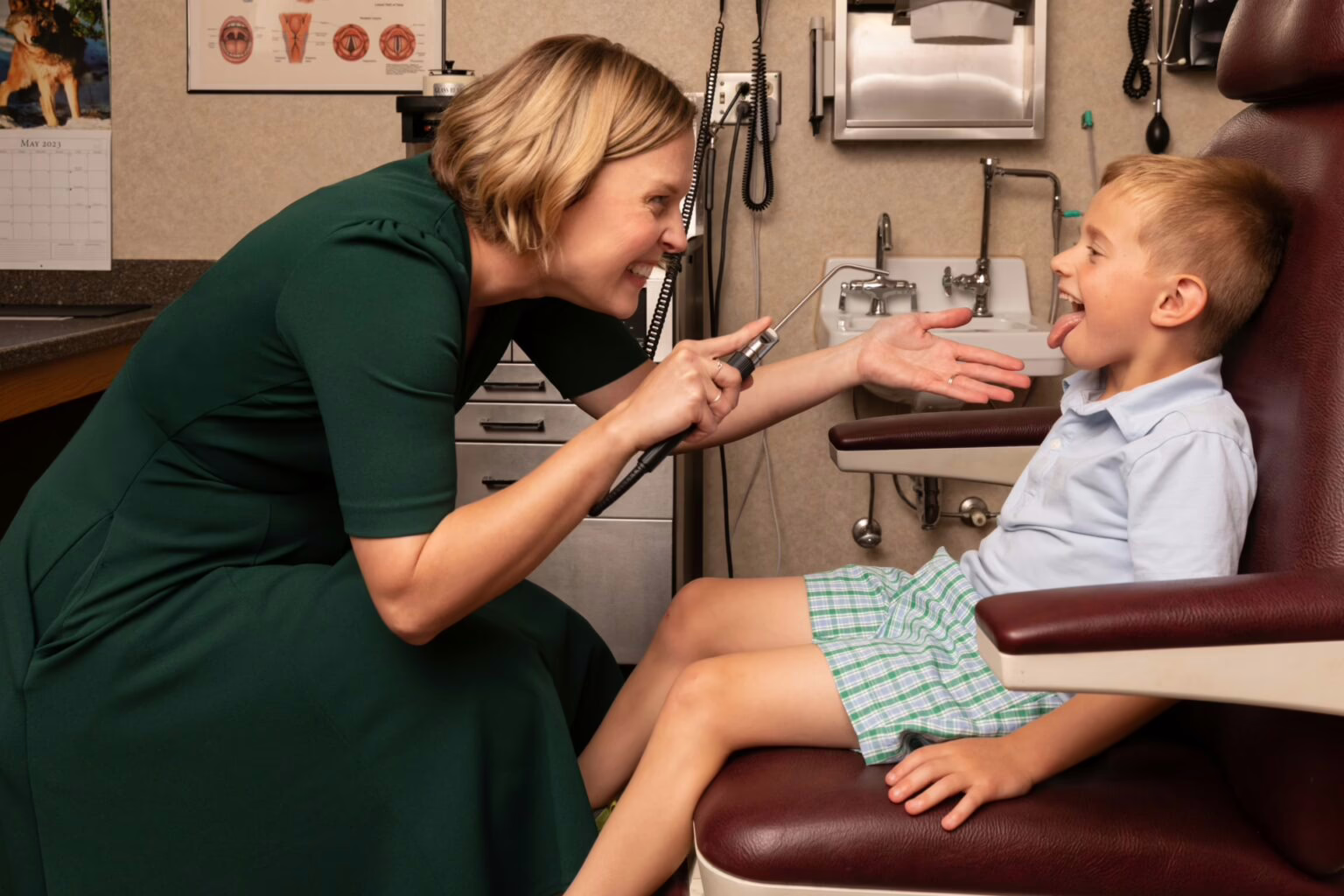 Pediatrics-Tonsil-Infection-exam ENT makes funny face as child sticks out tongue so tonsils can be observed