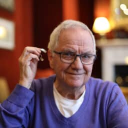 Happy man holding up his new hearing aid