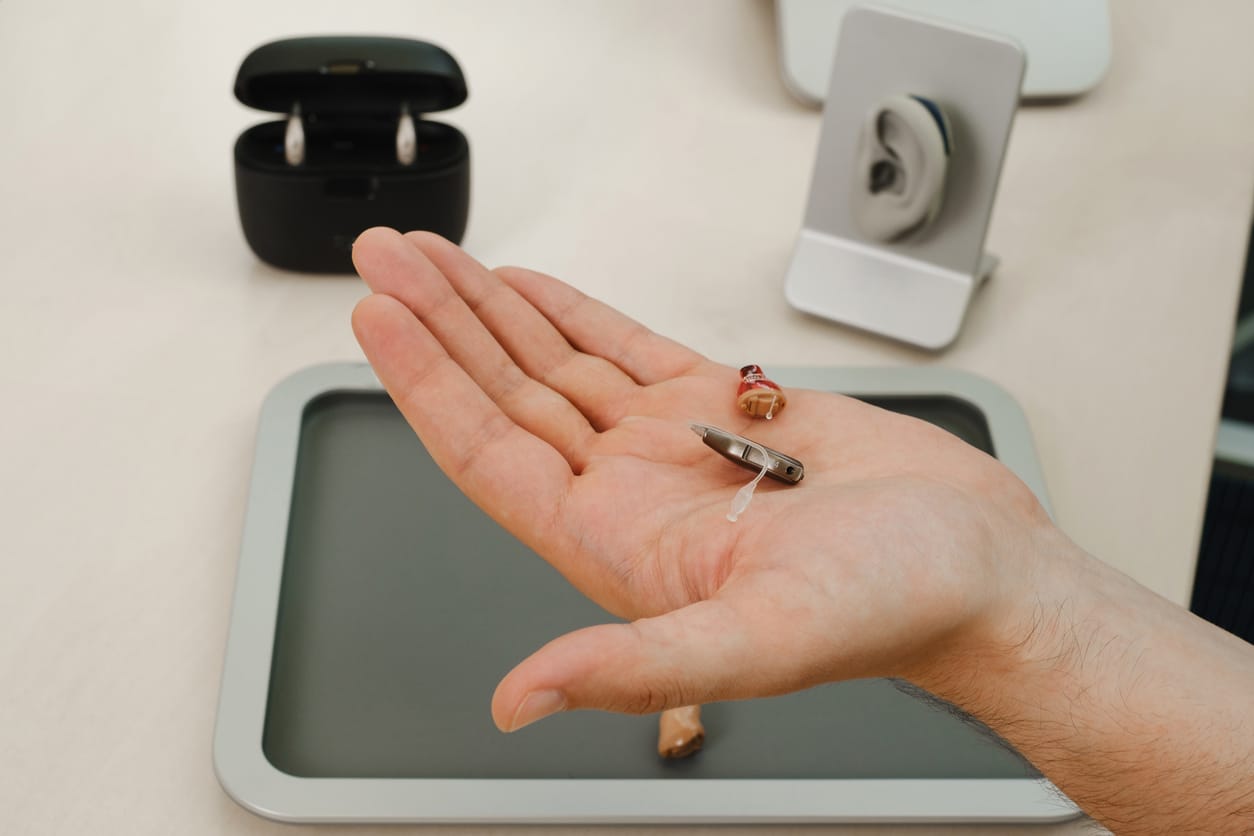 Very small hearing aid in hands.