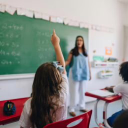ear view of a girl student raising her hand to ask on classroom at school