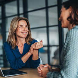 Two women having a focused and friendly conversation at a desk.