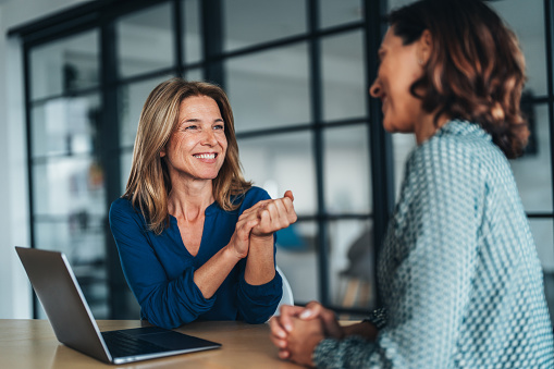 Two women having a focused and friendly conversation at a desk.