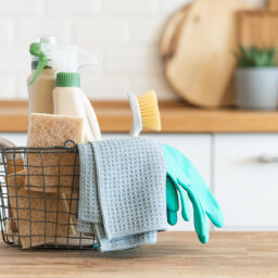 Basket of cleaning supplies sitting on a counter.