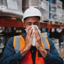 Man sneezing in the warehouse where he works