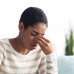 Woman with allergies pinching her nose.