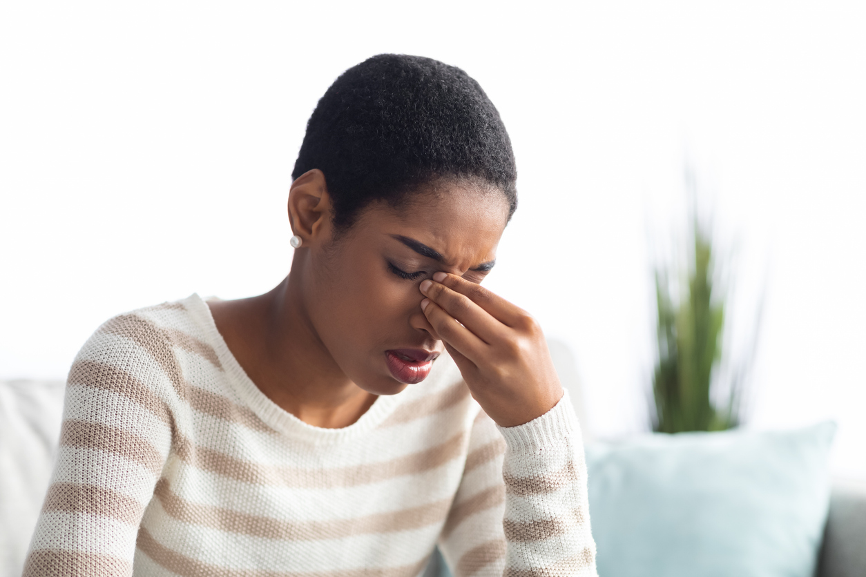 Woman with allergies pinching her nose.